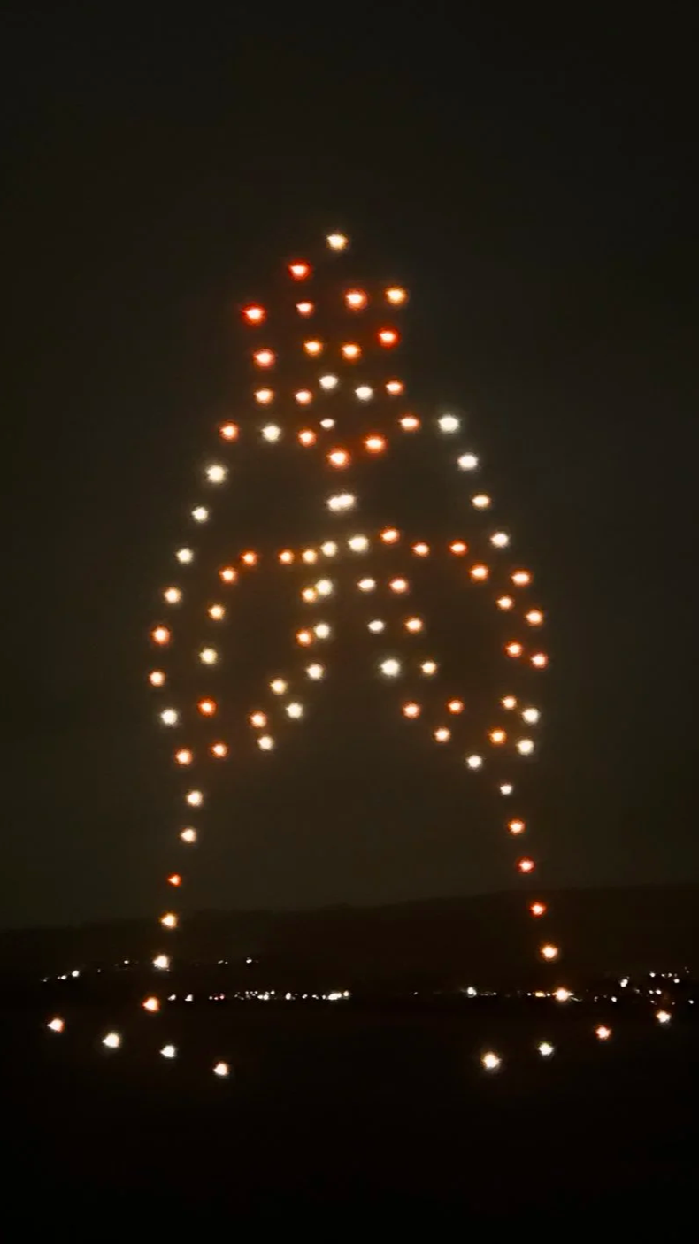 two champagne glasses "cheers" made with drones in a drone light show in the night sky
