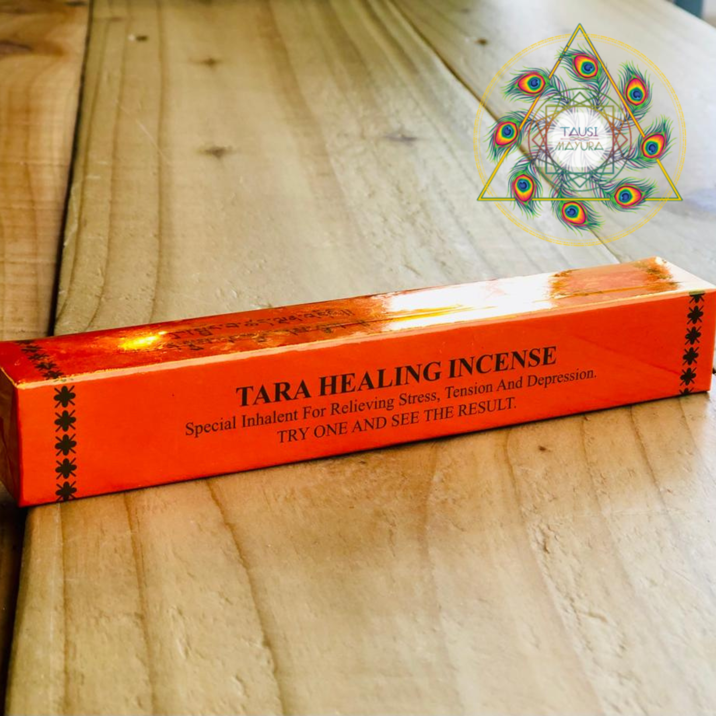 A box of Tara Healing Incense with an orange background, black text, and decorative black star patterns on the sides, placed on a wooden surface.