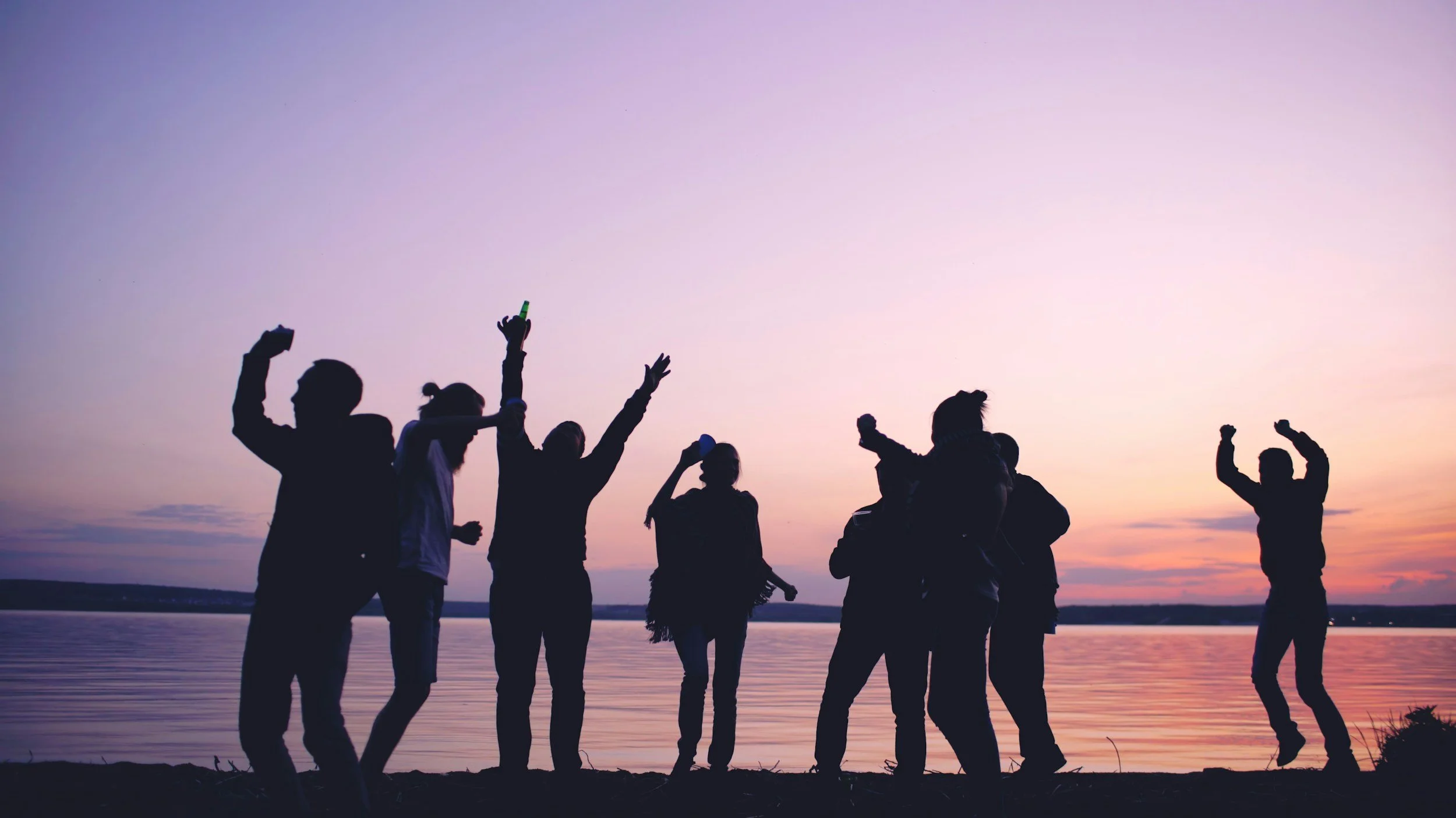 A group of people in silhouette celebrating on a beach