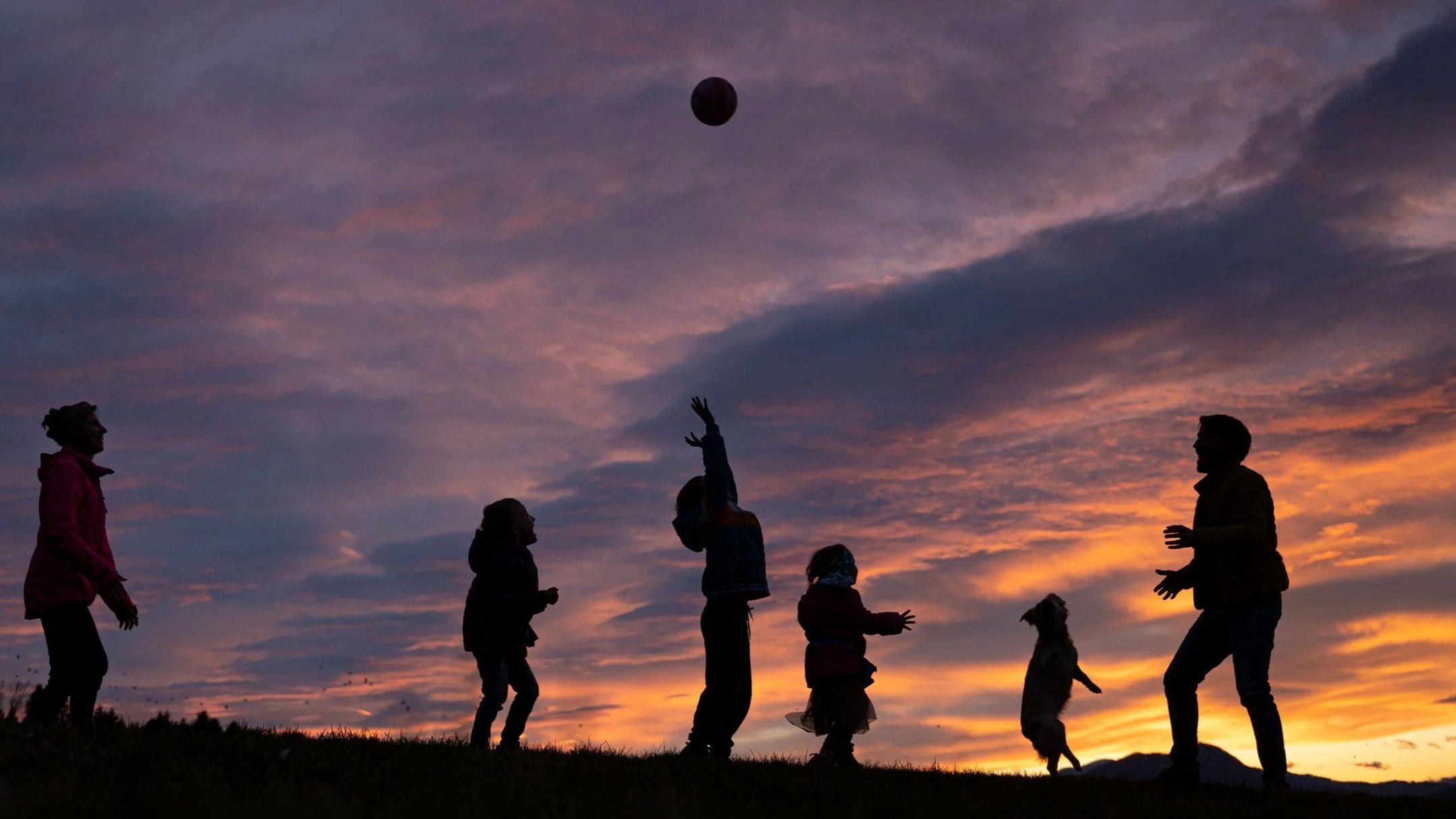Family playing catch at sunset