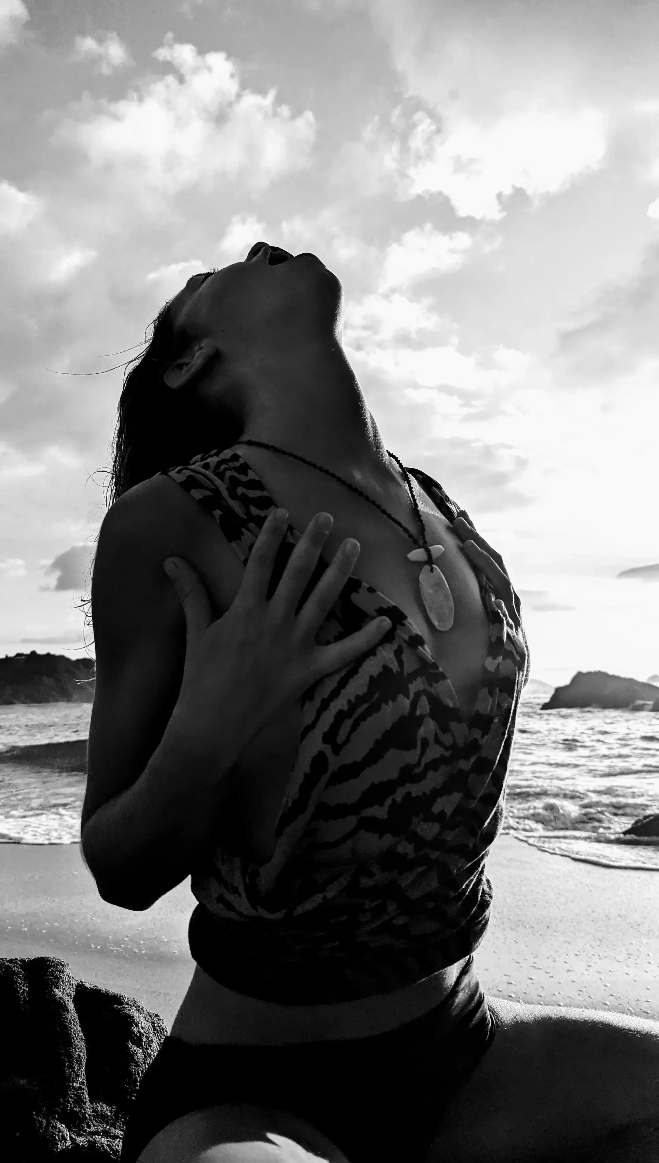 Verena Franzetti à genoux sur une plage, regardant vers le ciel, en noir et blanc.