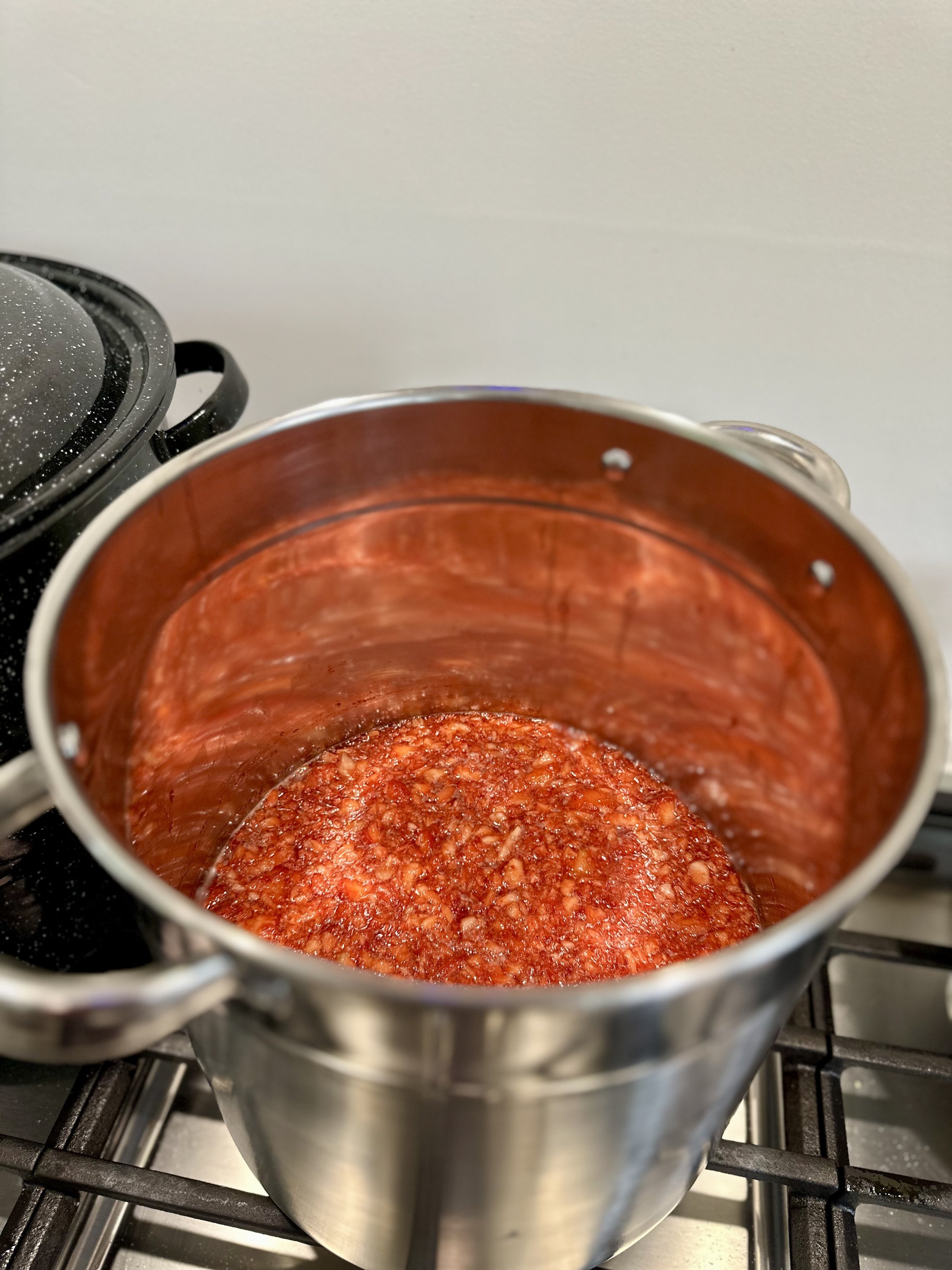 A pot of tomato sauce cooking on a stove.