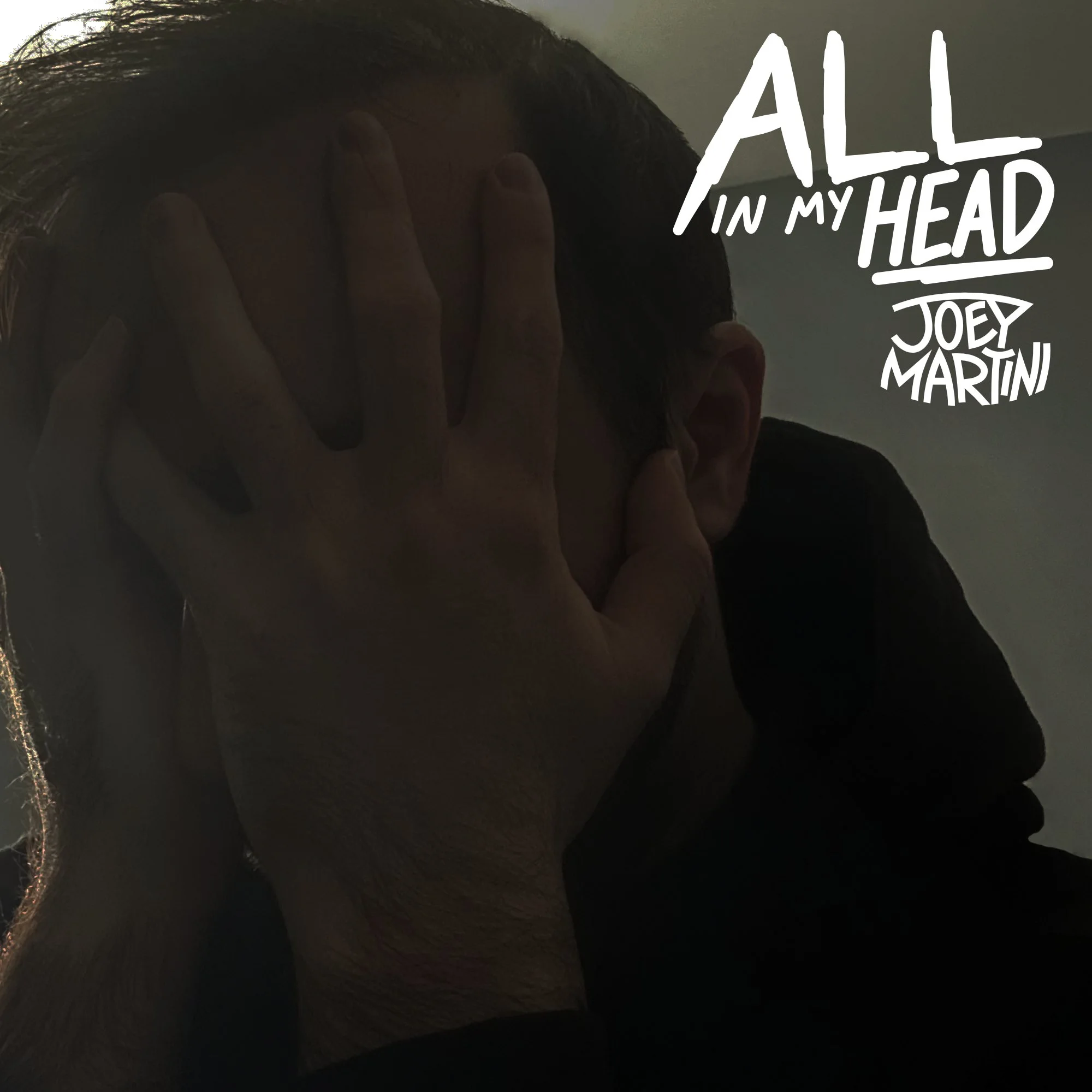 All In My Head single cover art featuring Joey covering his face with his hands in a barely lit room, with the song’s and Joey’s logo in the top right corner.