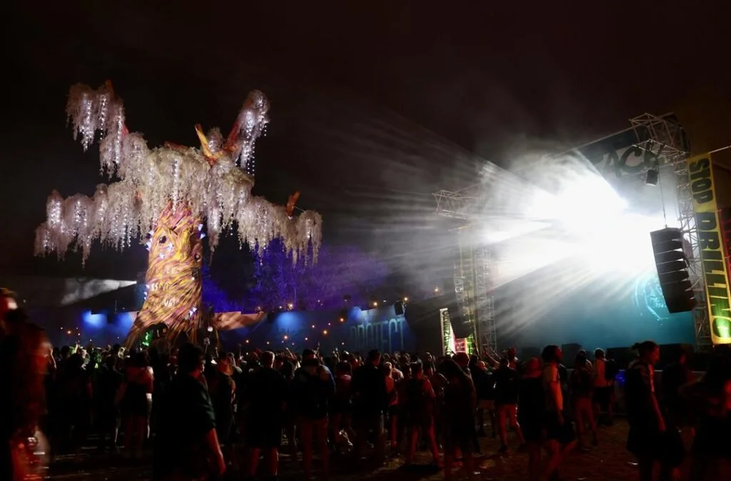 Crowd at nighttime music festival near luxury boutique glamping area