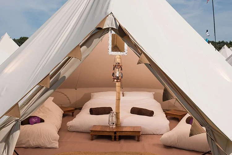 Bright Classic Bell Tent with a double and 2 single beds, towels, mirror and a hanging lantern, styled for luxury boutique camping comfort