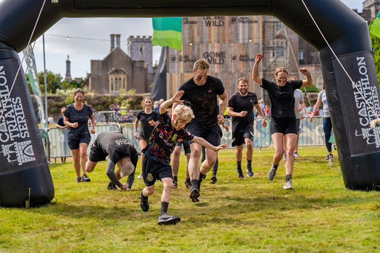 Festival-goers celebrating at the finish line at outdoor event near boutique glamping village