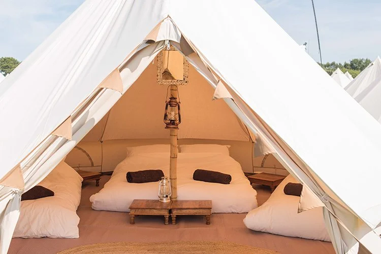 Classic Bell tent interior with cosy bed, towels, and lantern at boutique glamping site