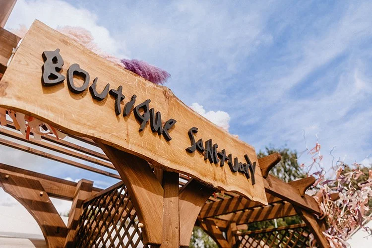 Wooden ‘Boutique Sanctuary’ entrance sign at luxury glamping campsite