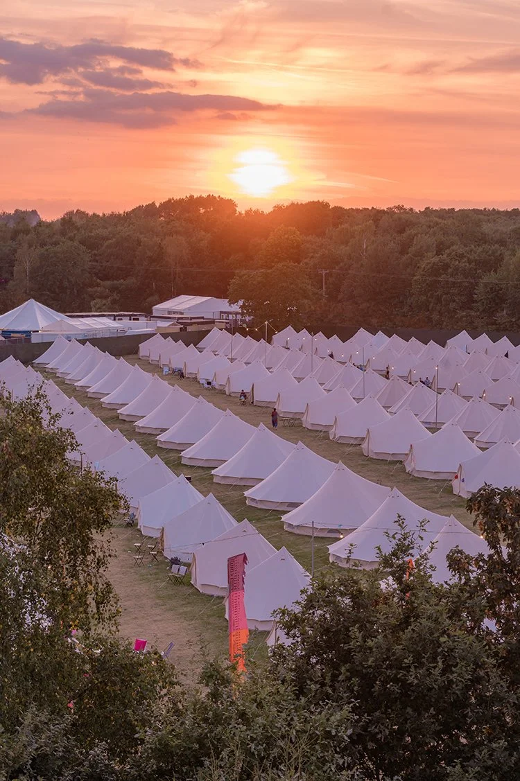 Sunset over a field of bell tents at one of our glamping events