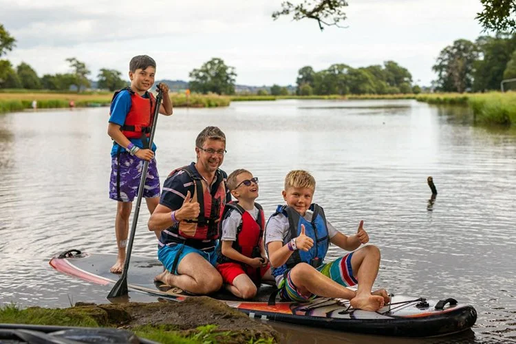 Family paddleboarding and relaxing by the lake near boutique glamping site