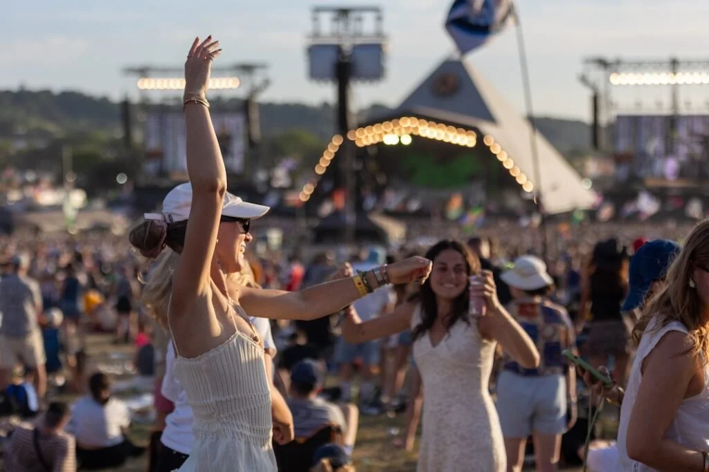 Festival goers dancing at sunset near the pyramid stage at Glastonbury near our glamping site.
