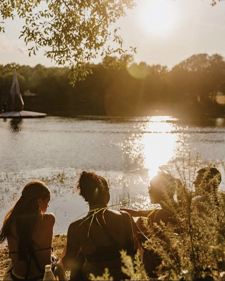 Guests relaxing by the lakeside at sunset near boutique glamping site 