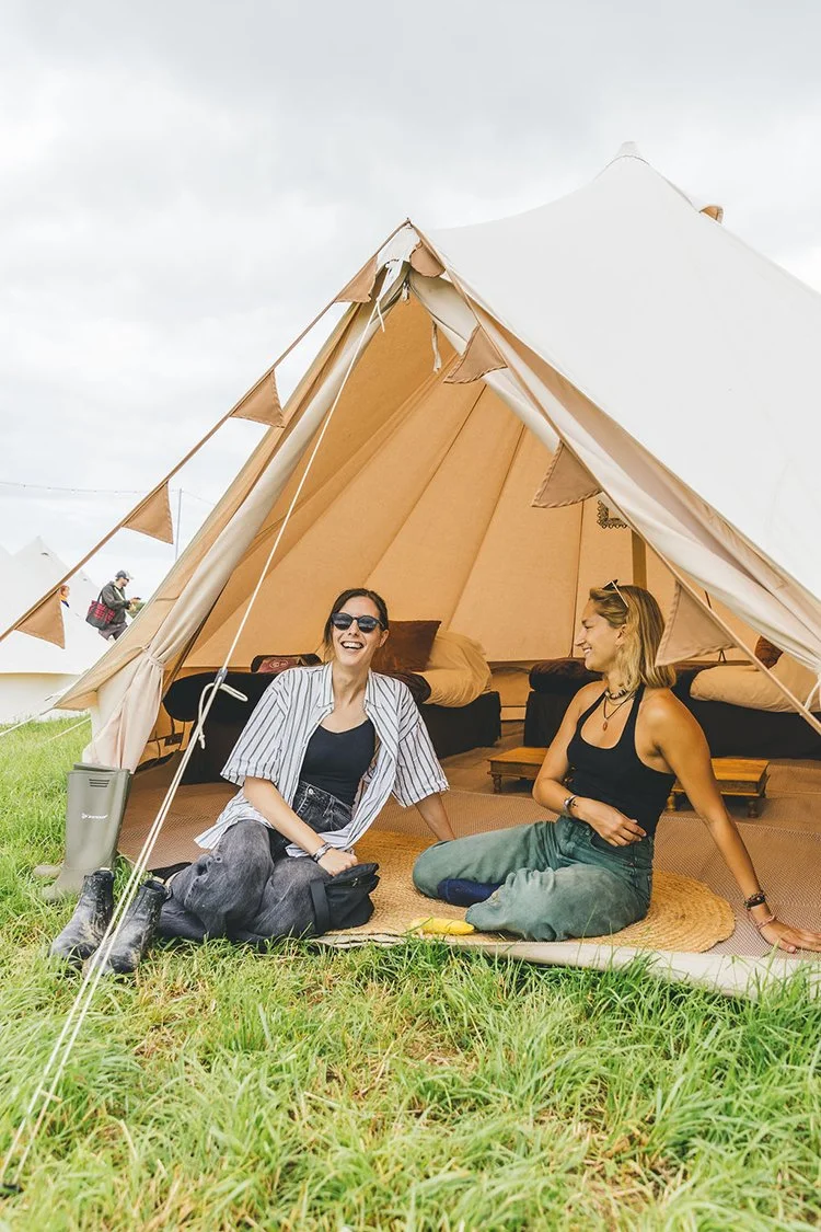 Guests hanging outside their bell tent at a glamping event.