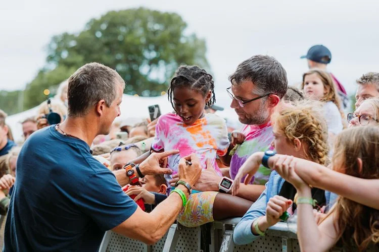 Festival acts signing autographs for children at outdoor boutique camping and glamping event