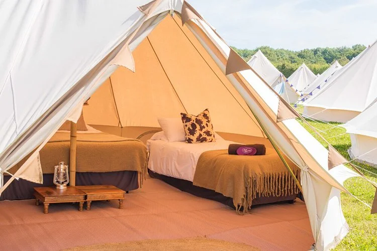 	
Deluxe Bell tent with twin beds, rustic wooden table, and lantern at boutique glamping village.