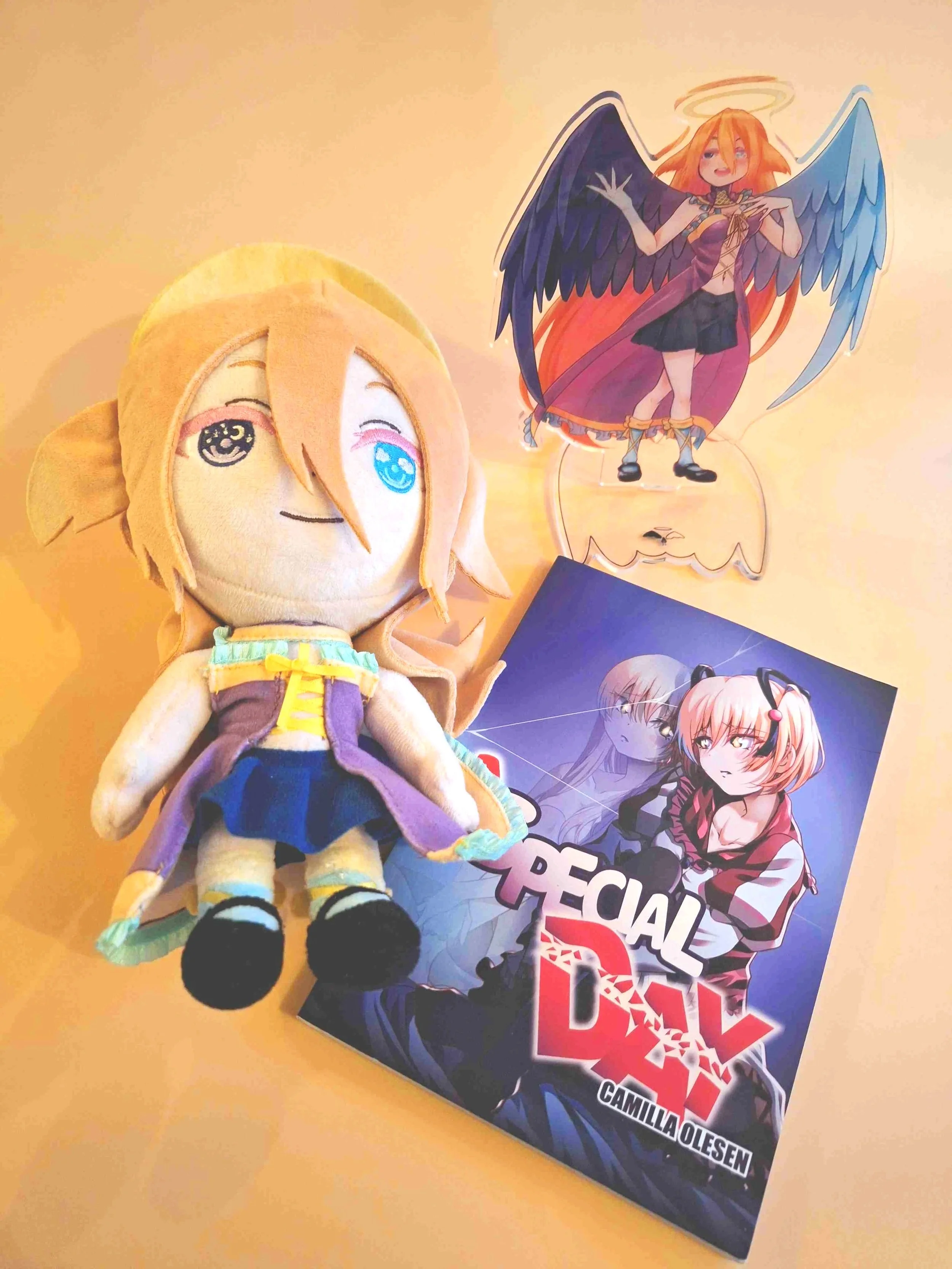 Orange haired plush with different colored eyes and a book called A Special Day and standee angel