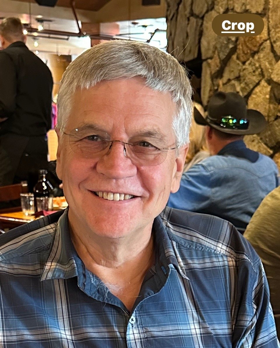 Dr. Leigh in glasses and a plaid shirt in a restaurant setting.
