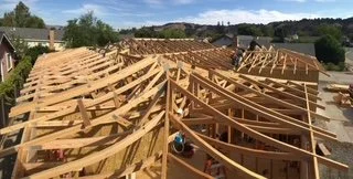 Construction site with wooden framework for building roof or ceiling.