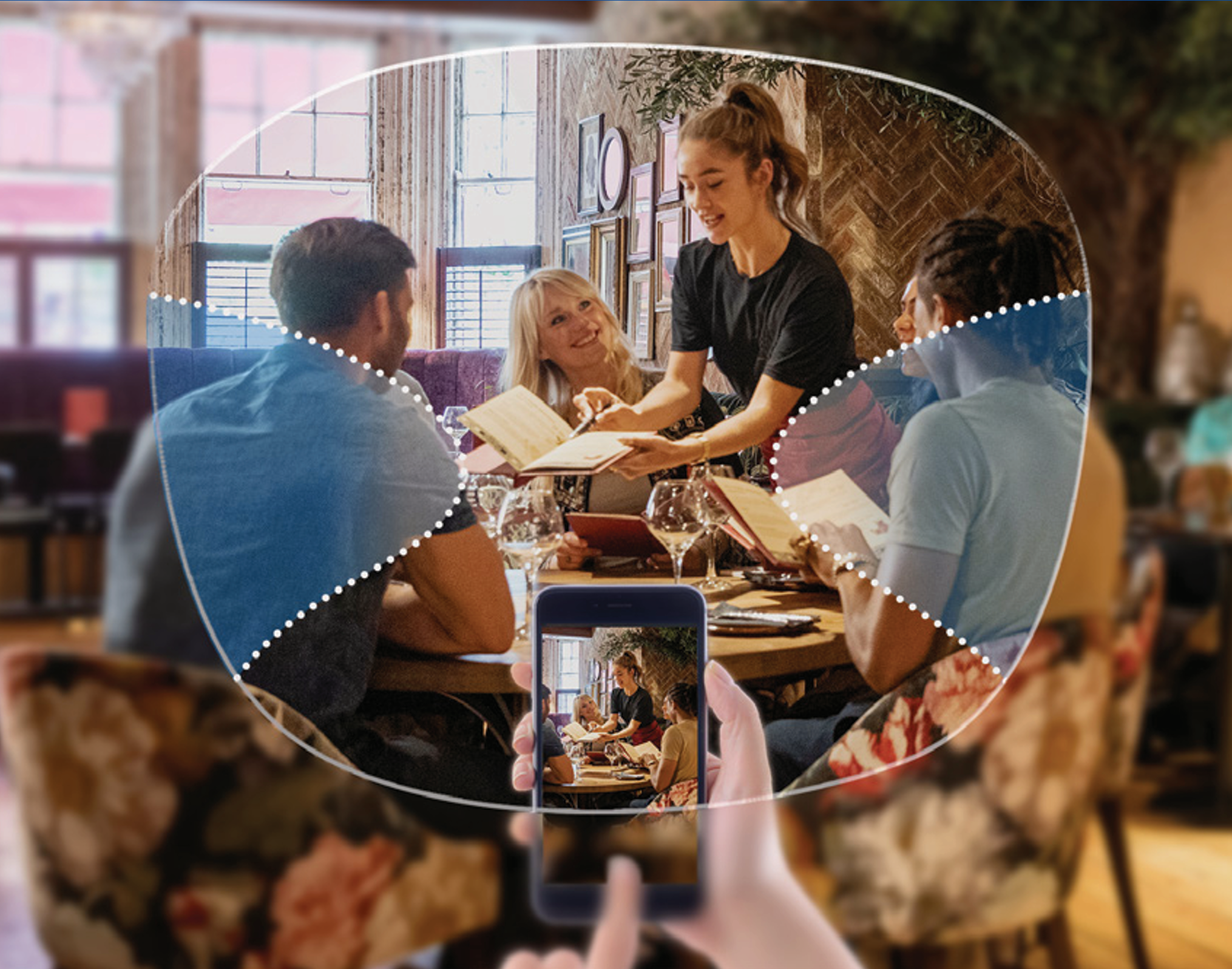 People dining at a restaurant, with one person taking a photo of the group with a smartphone, highlighting the scene with augmented reality overlay.