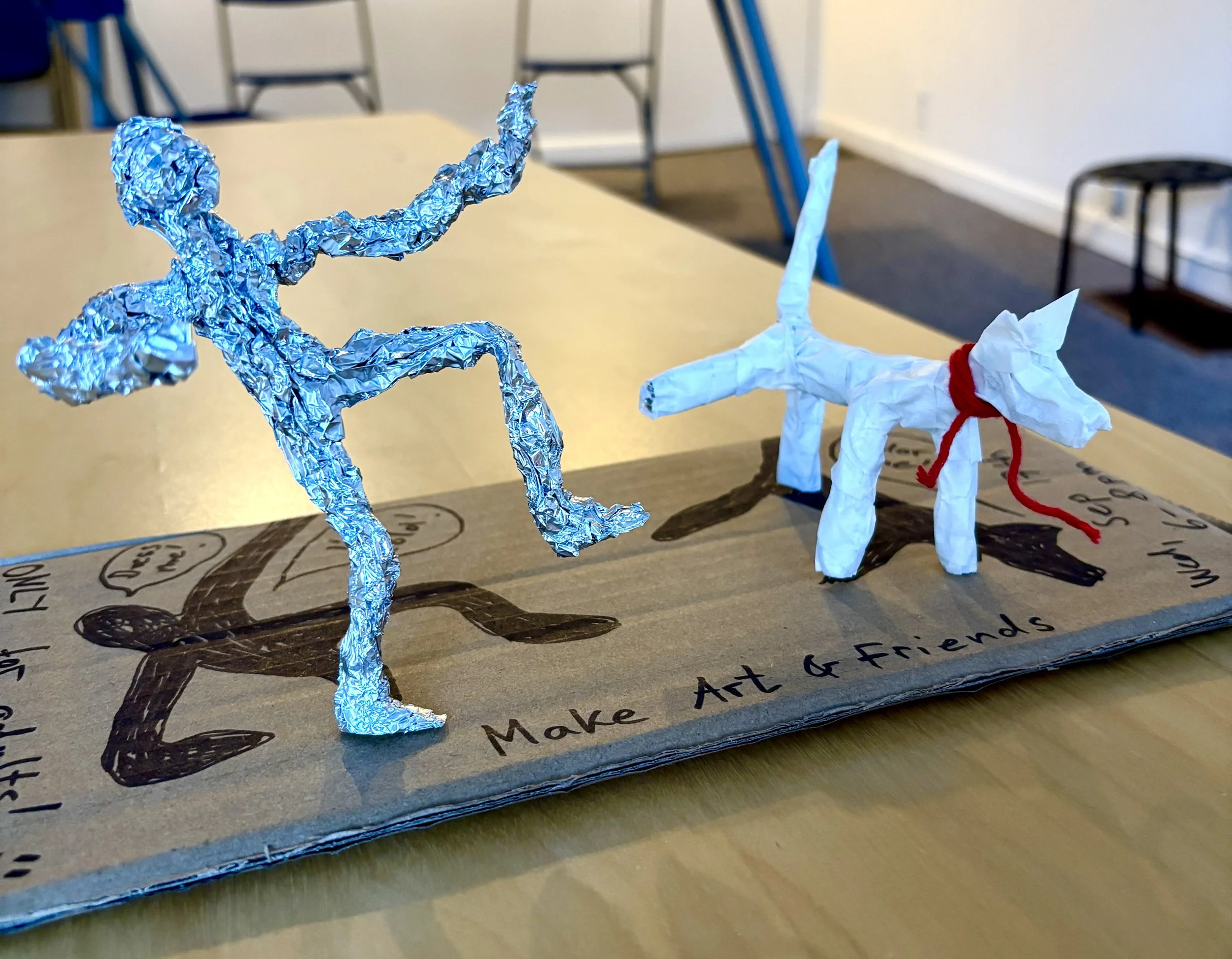 Handcrafted tin foil figures of a dancing person and a dog