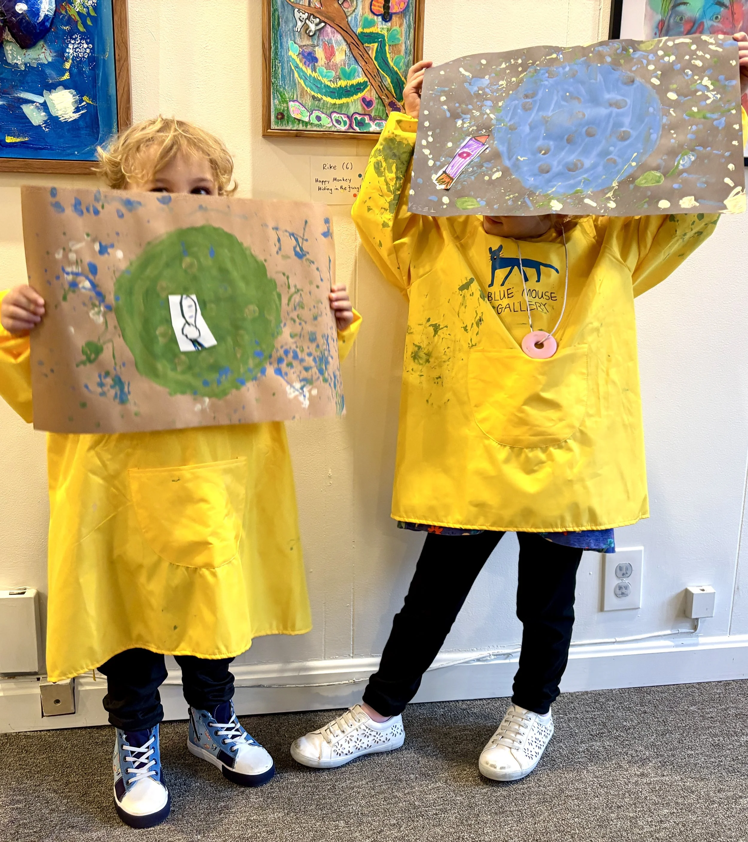 Two children proudly showing their artwork