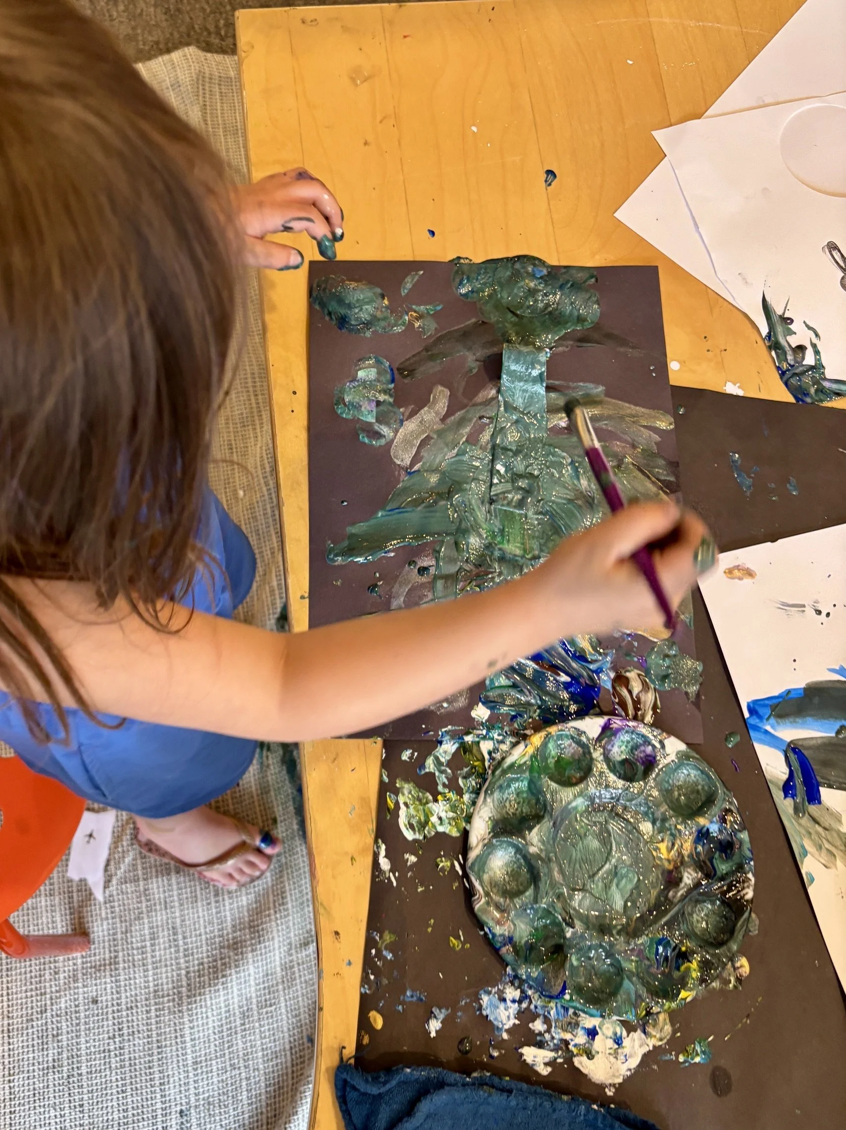 A young child mixing paints and creating art during Open Studio time