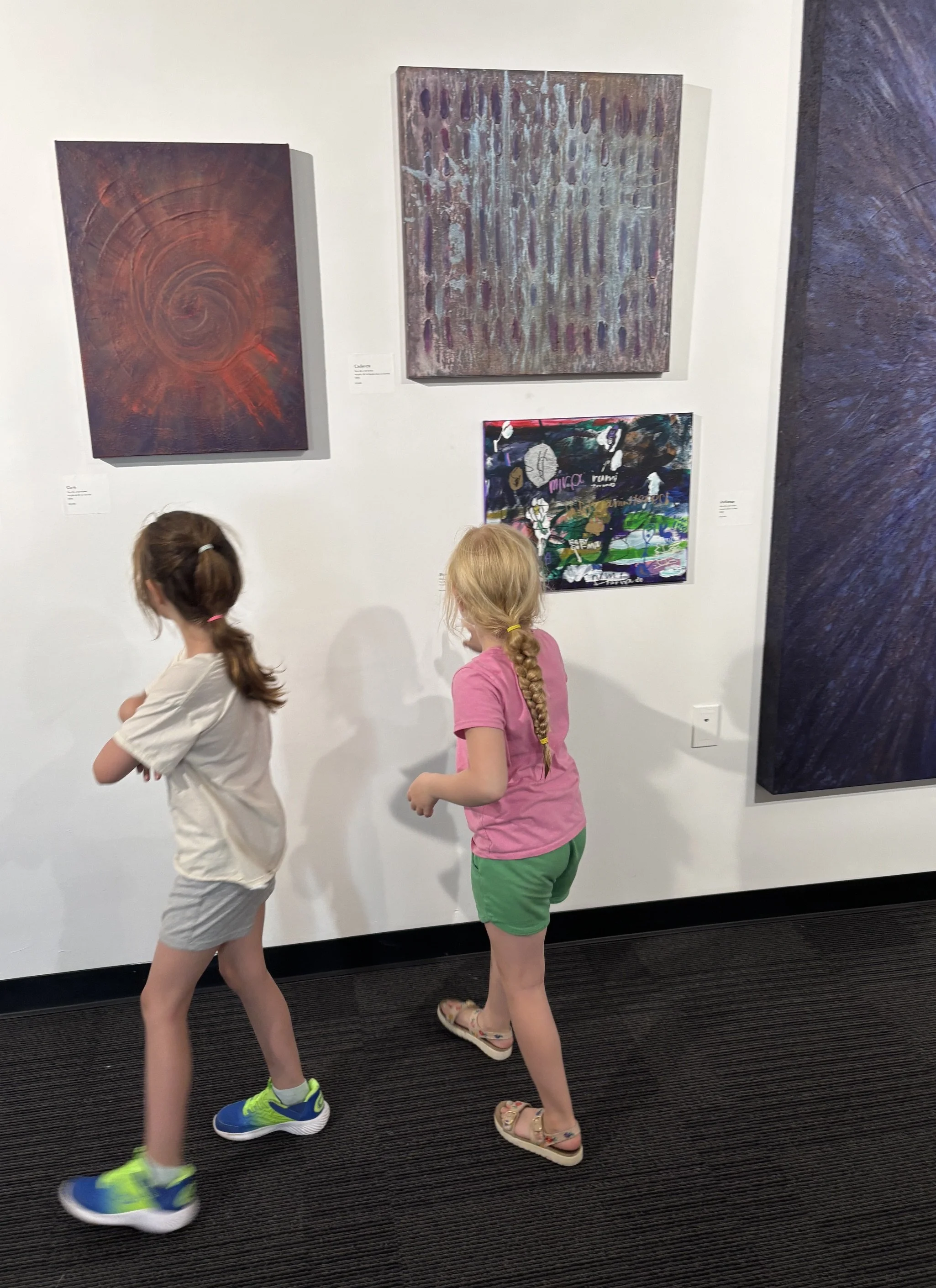 Children looking at artwork at an exhibition that combines adult and children's artwork