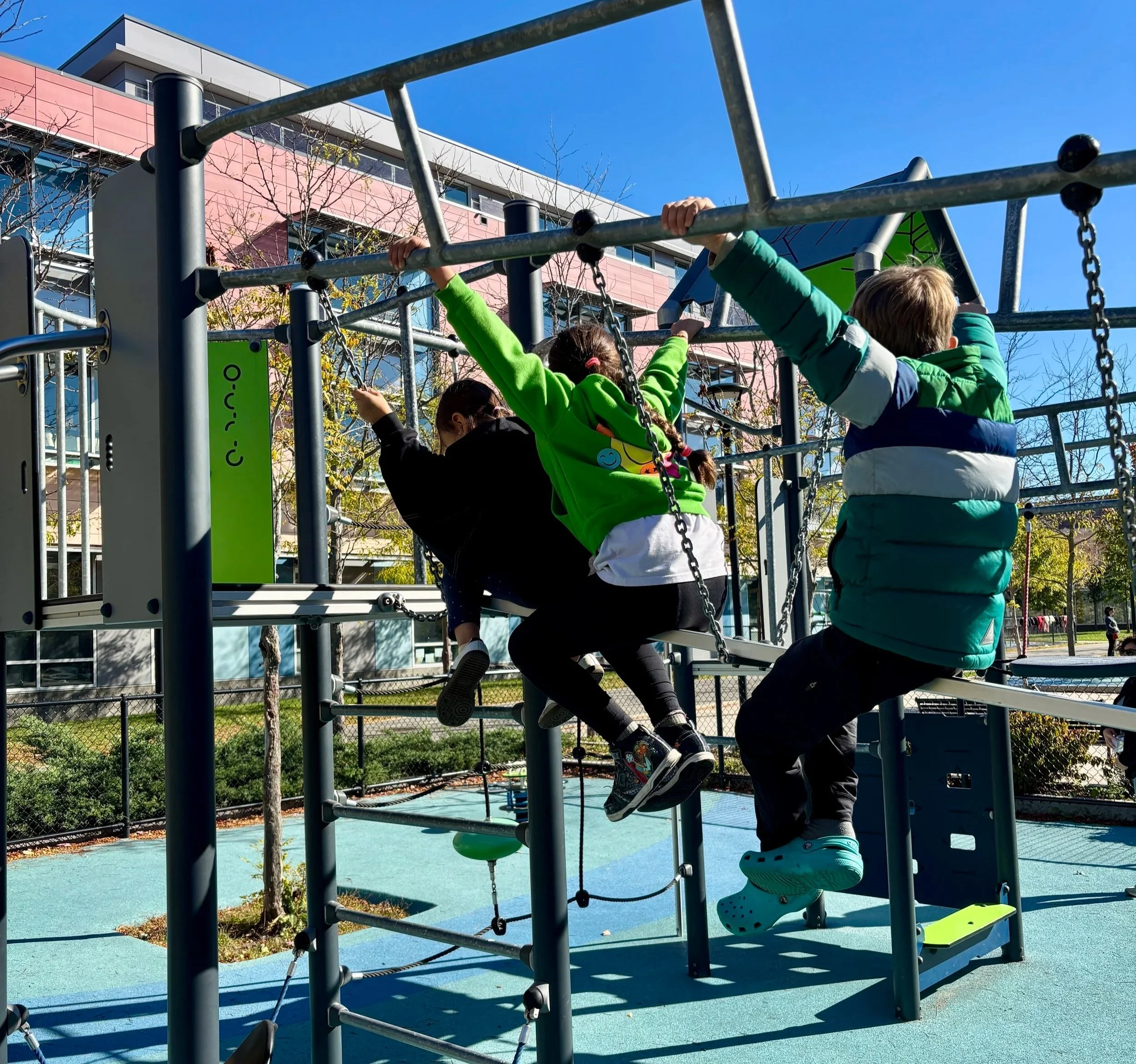 Three children playing on the playground during a vacation program