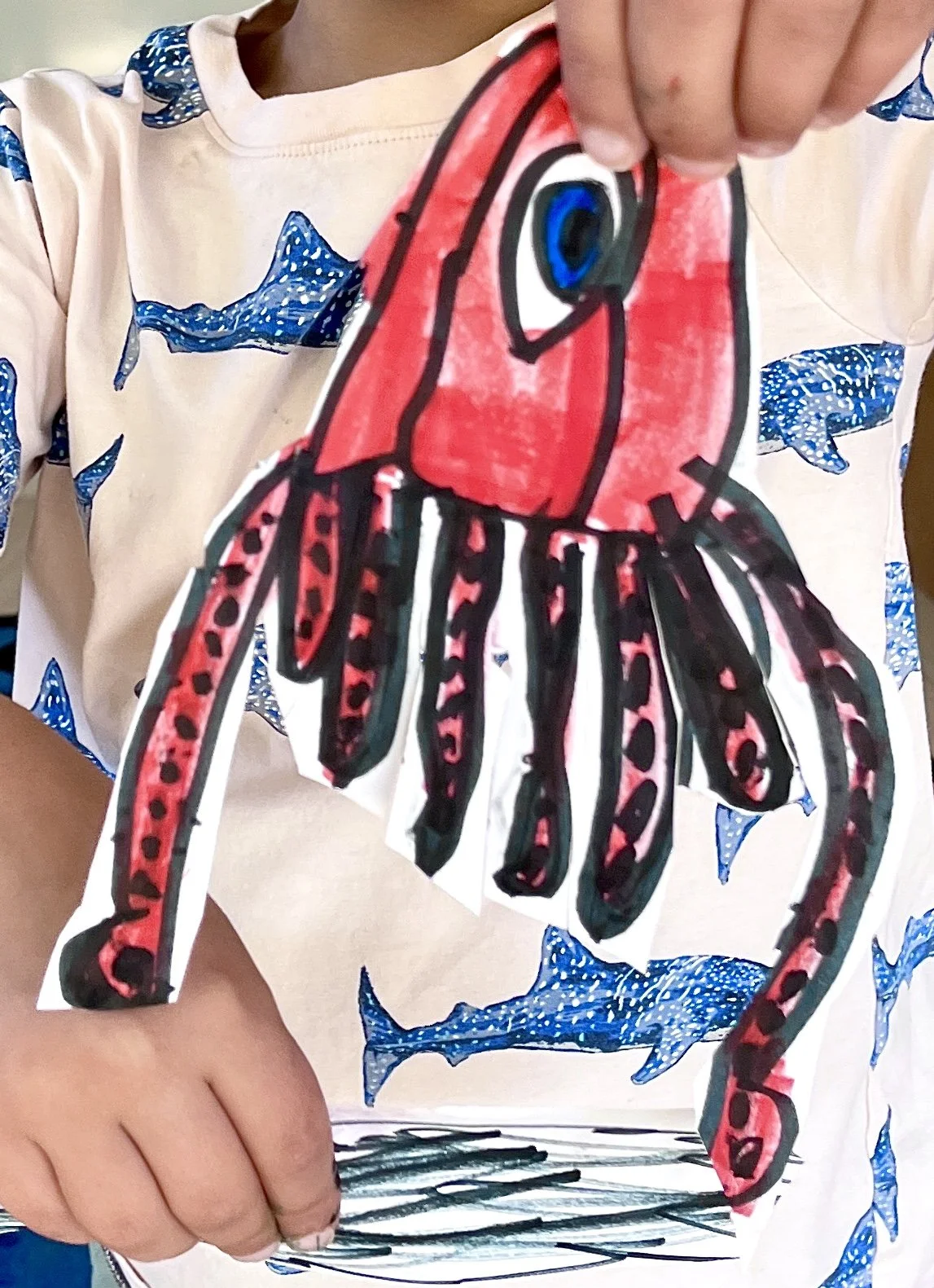 Child holding a colorful, hand-drawn octopus paper craft