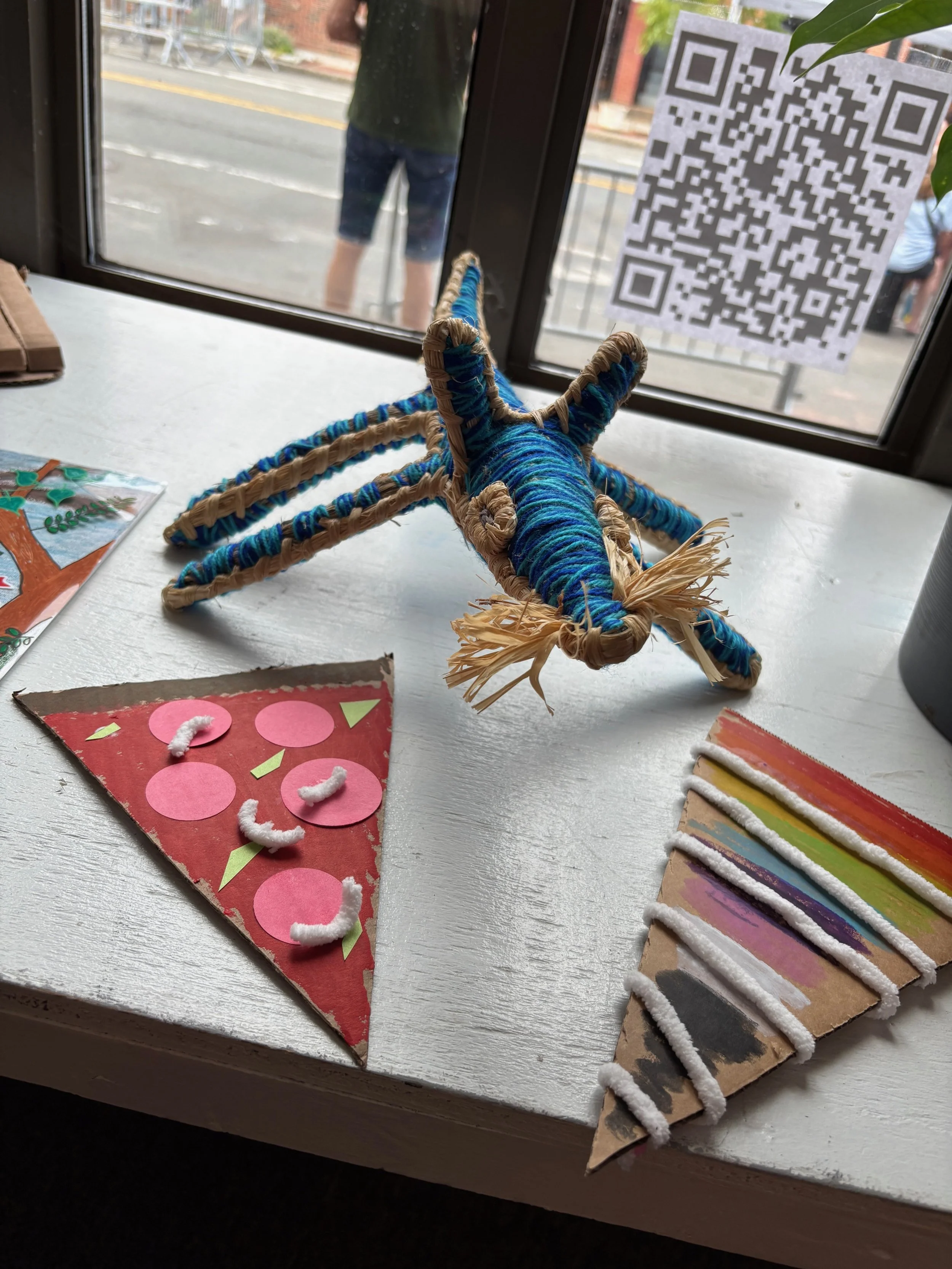 Two pieces of pizza crafted from cardboard with a blue mouse mascot in the background