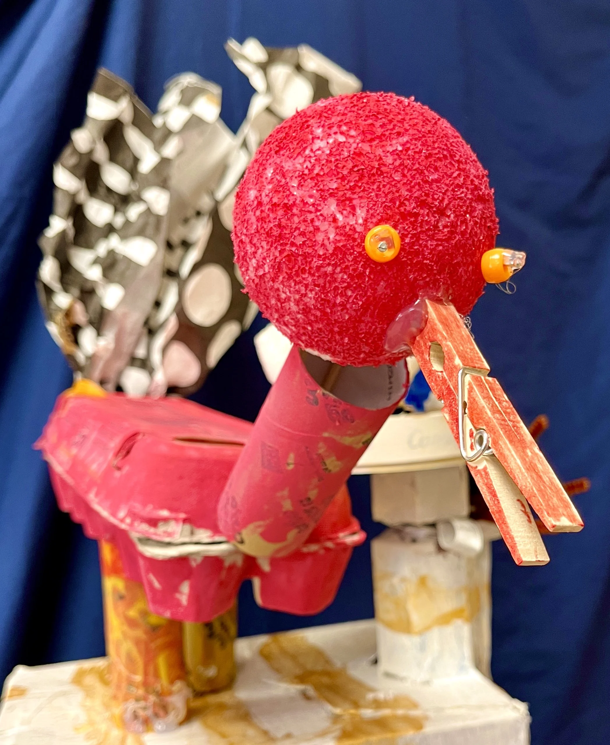 A colorful, handcrafted sculpture of a red bird