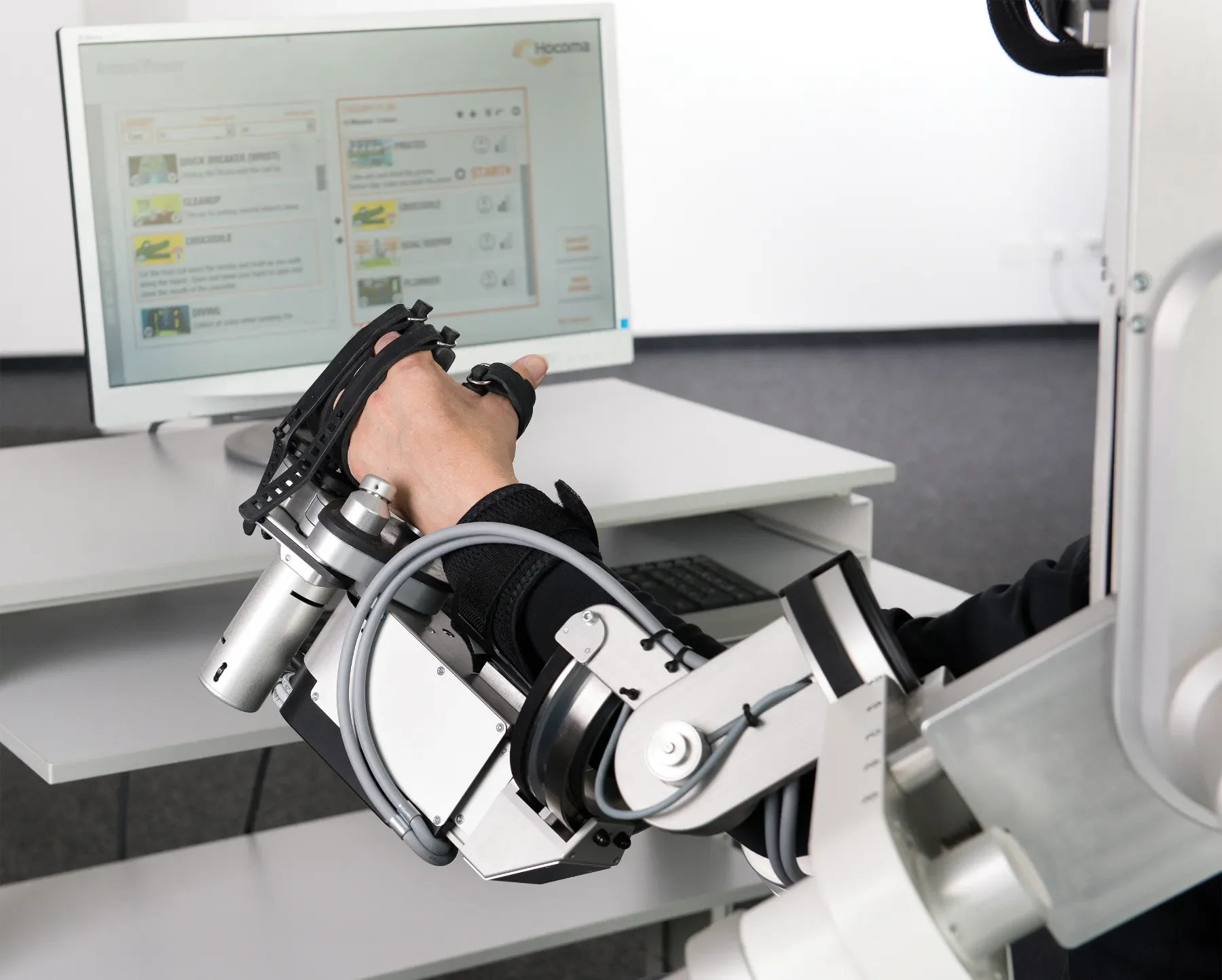 Paciente usando Armeo Power combinado con Manovo Power para terapia robótica de mano y brazo con feedback en pantalla. Bayber es distribuidor oficial en España y Portugal