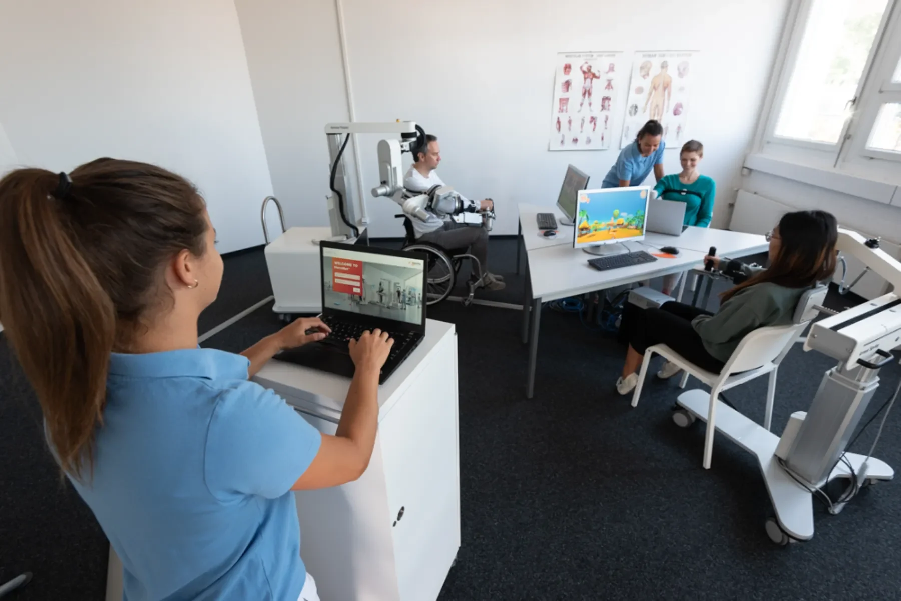 Paciente adulto realizando reeducación funcional del brazo con Armeo Power mientras la terapeuta ajusta los parámetros en pantalla. Bayber España