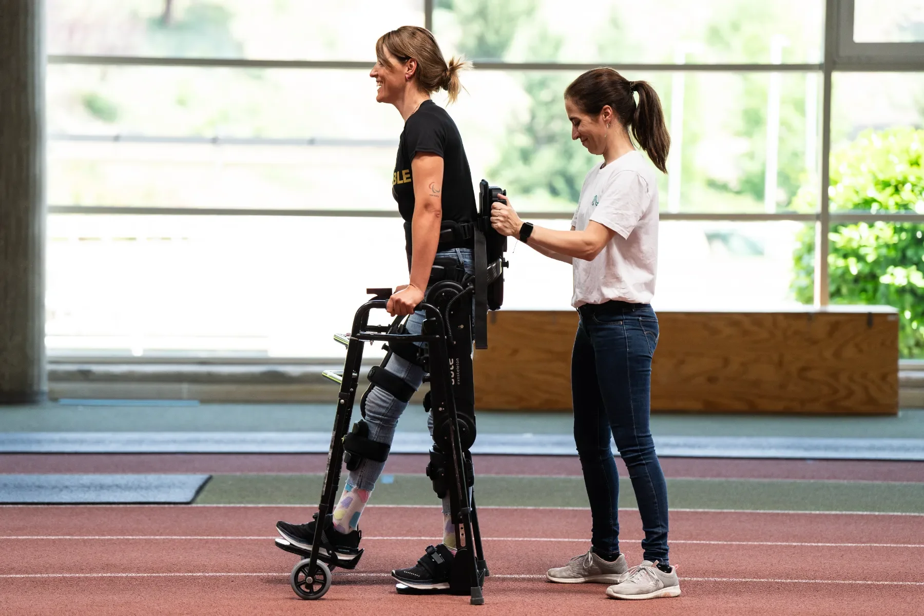 Fisioterapeuta ayudando a una paciente a mantenerse en bipedestación y caminar con ABLE Exoskeleton y andador. Bayber es distribuidor oficial en Portugal