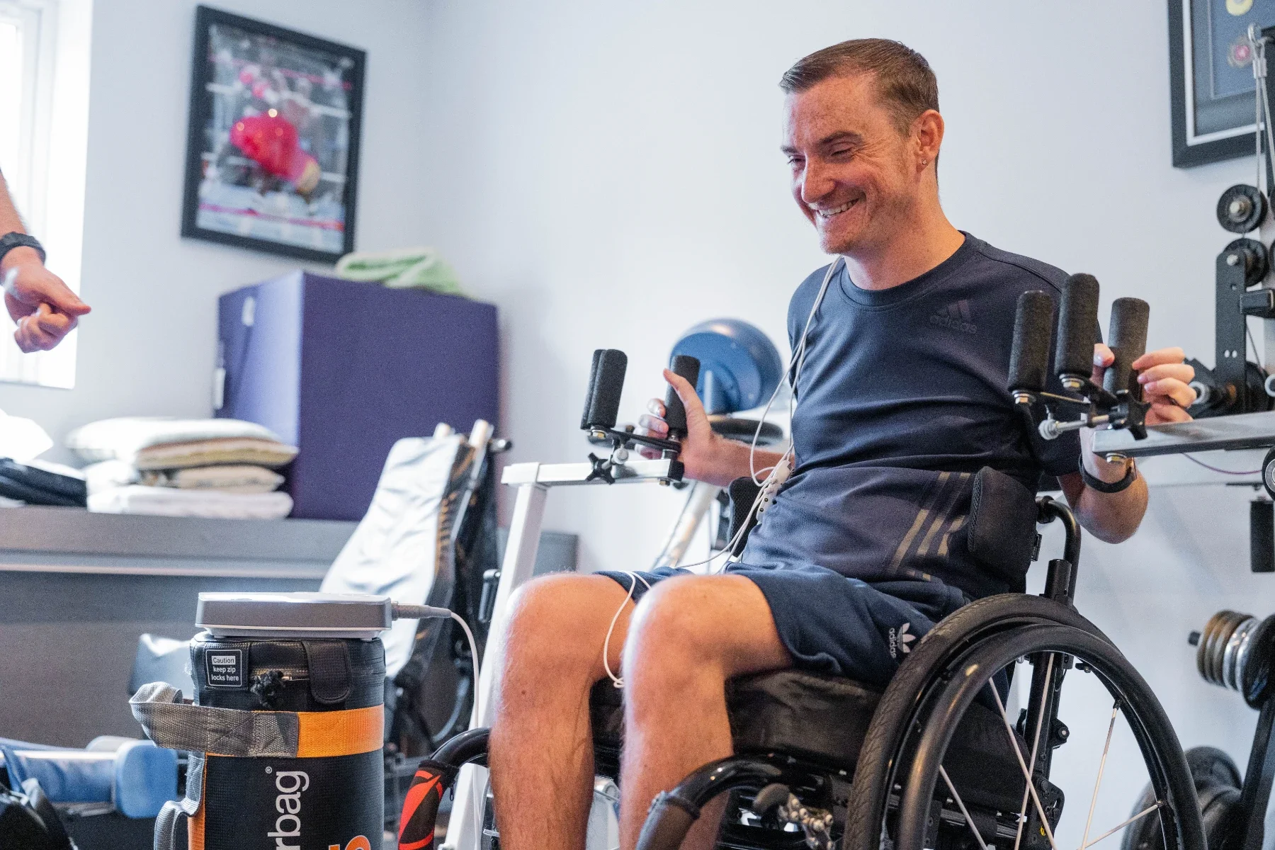 Paciente con lesión medular entrenando fuerza de miembro superior en silla de ruedas mientras recibe estimulación con Onward ARCEX