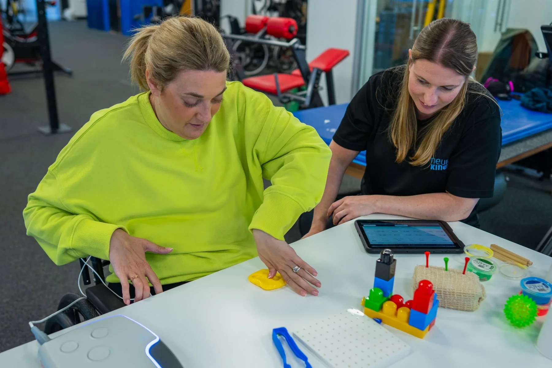 Paciente en silla de ruedas realizando ejercicios de función manual en sesión de terapia ocupacional, monitorizada con tablet vinculada a Onward ARCEX