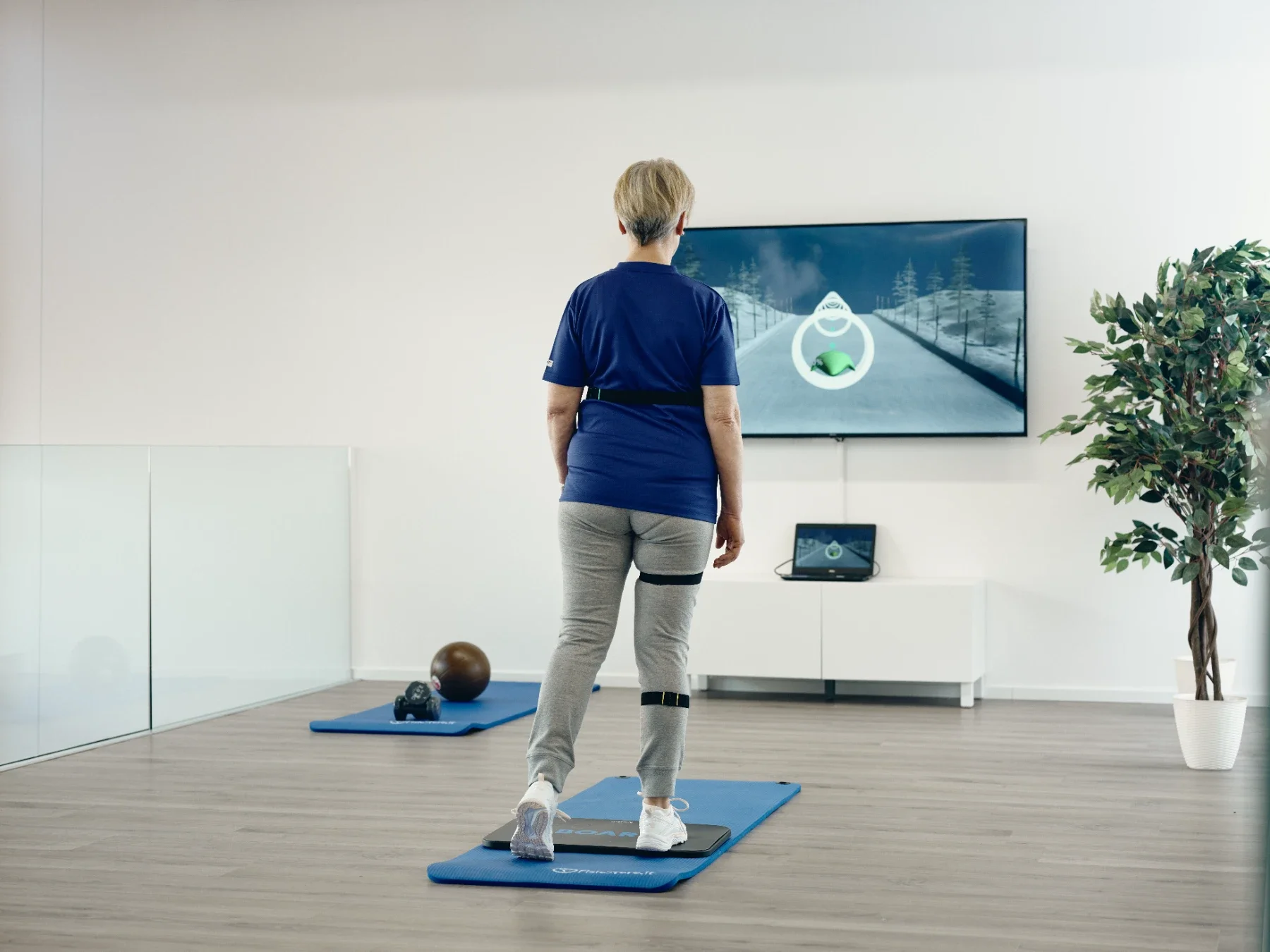 Paciente realizando marcha y cambios de apoyo sobre la plataforma Euleria Lab mientras sigue un recorrido proyectado en la pantalla