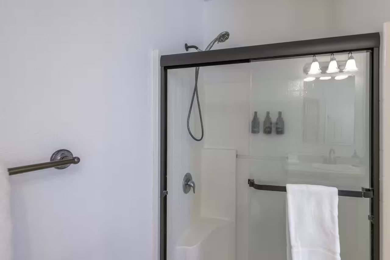 Bathroom with glass shower door, towel rack, and shower head