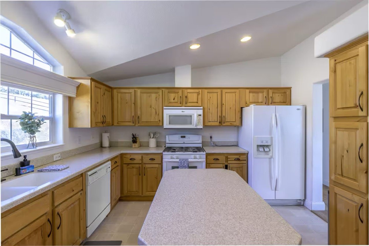 Modern kitchen with wooden cabinets, white appliances, and a center island.