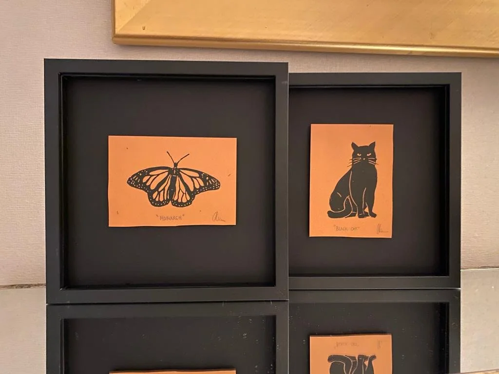 Four framed illustrations of animals and a butterfly on orange backgrounds, including a monarch butterfly, a black cat, and a gorilla.