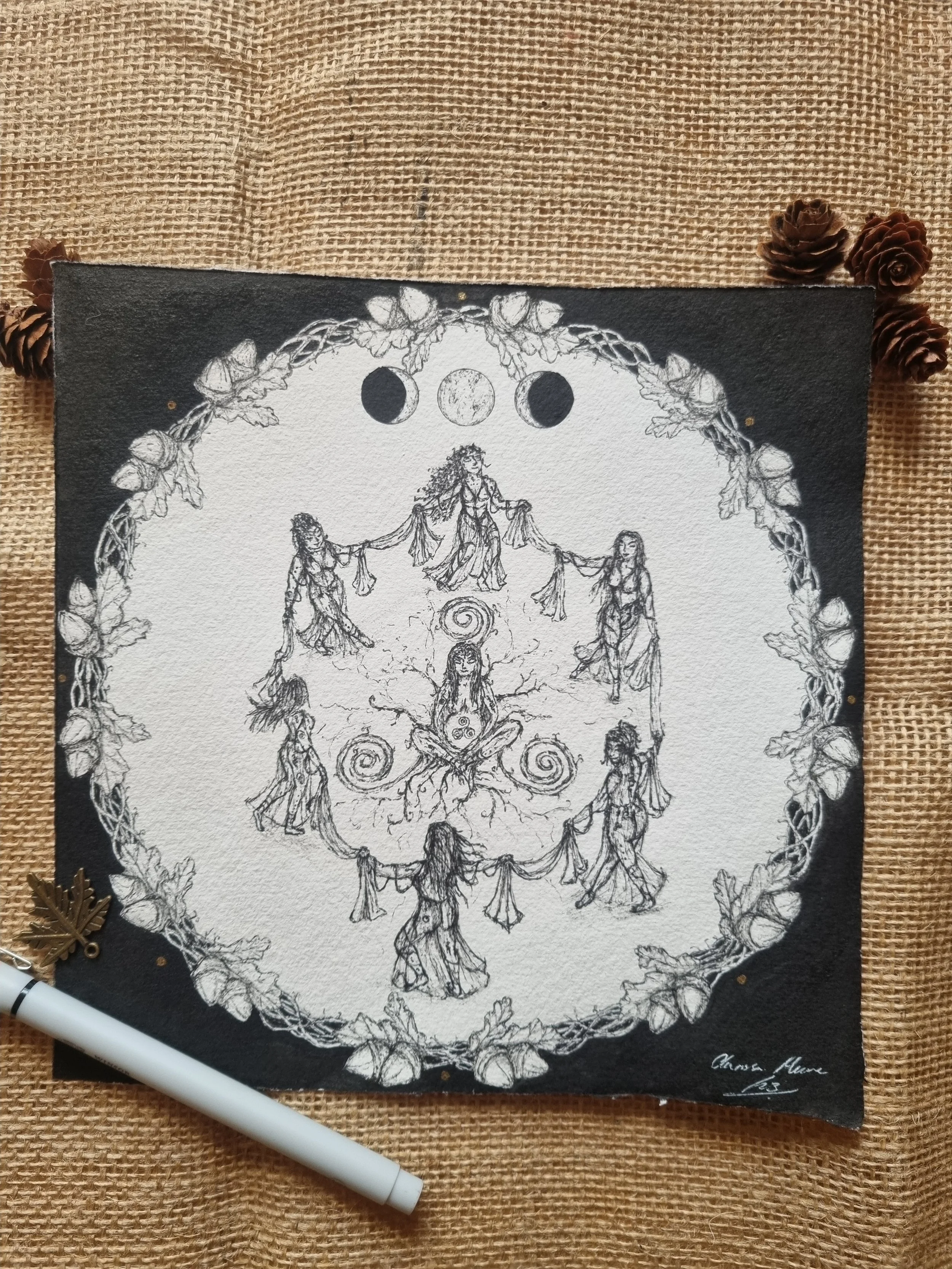 A black and white illustration of mystical figures arranged in a circular pattern, surrounded by a leaf and vine border, with phases of the moon at the top.