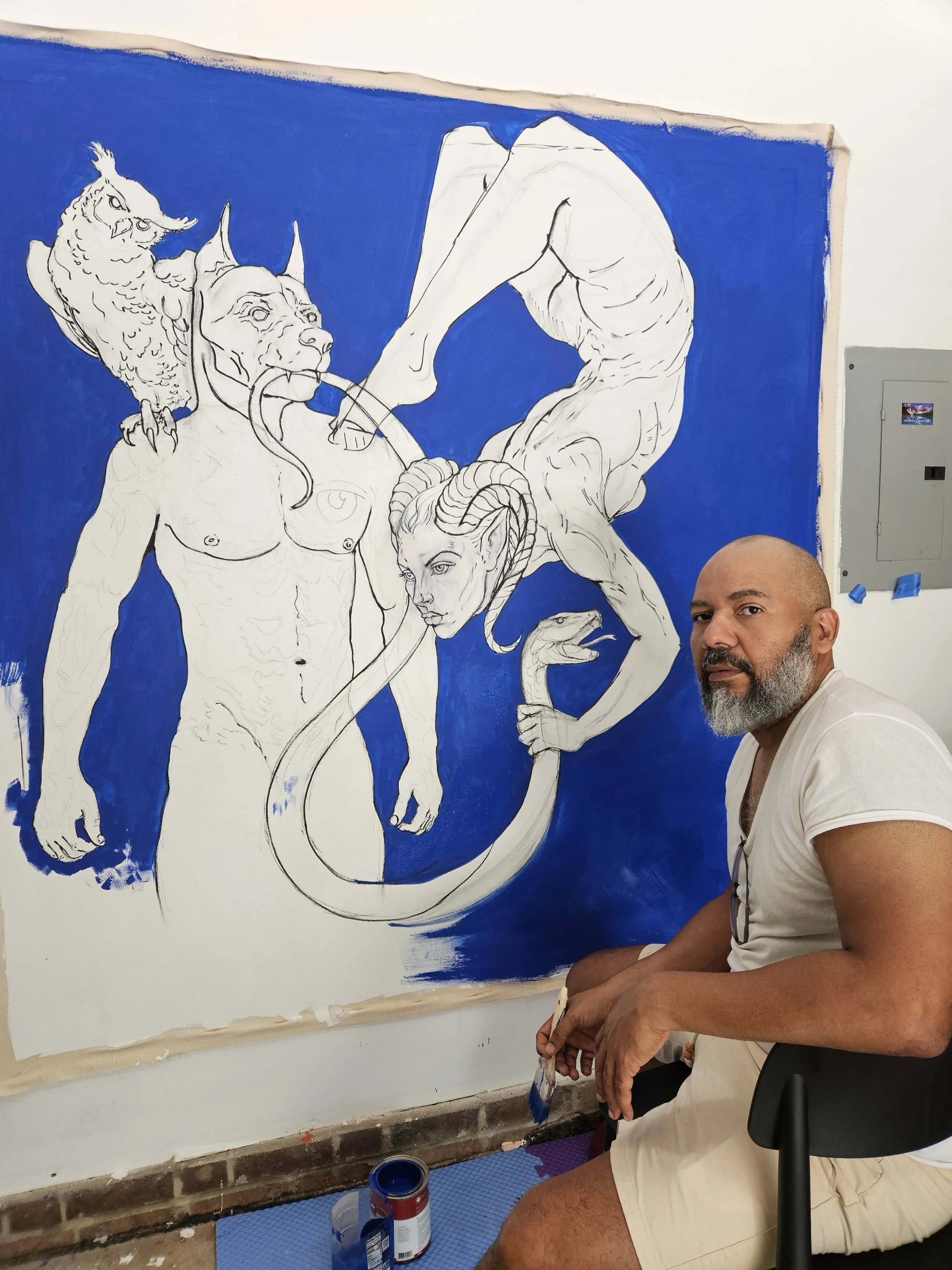 Edward Telleria in his studio beside Plenitude at the drawing stage, the figures sketched in white on a blue canvas