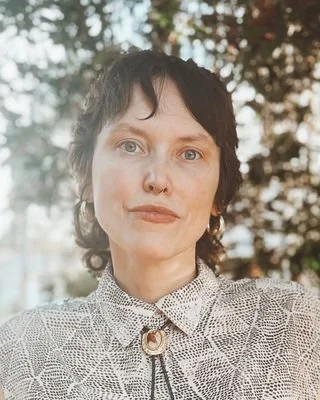 Woman outdoors with short hair and patterned blouse