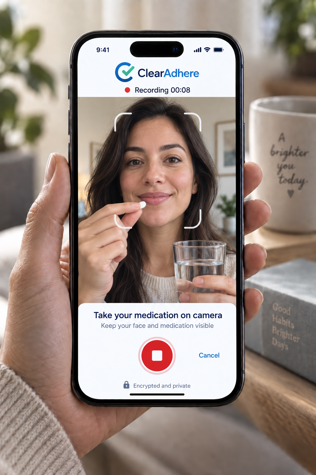 A woman takes medication on camera using a smartphone app, with a glass of water in her hand, in a cozy home setting.