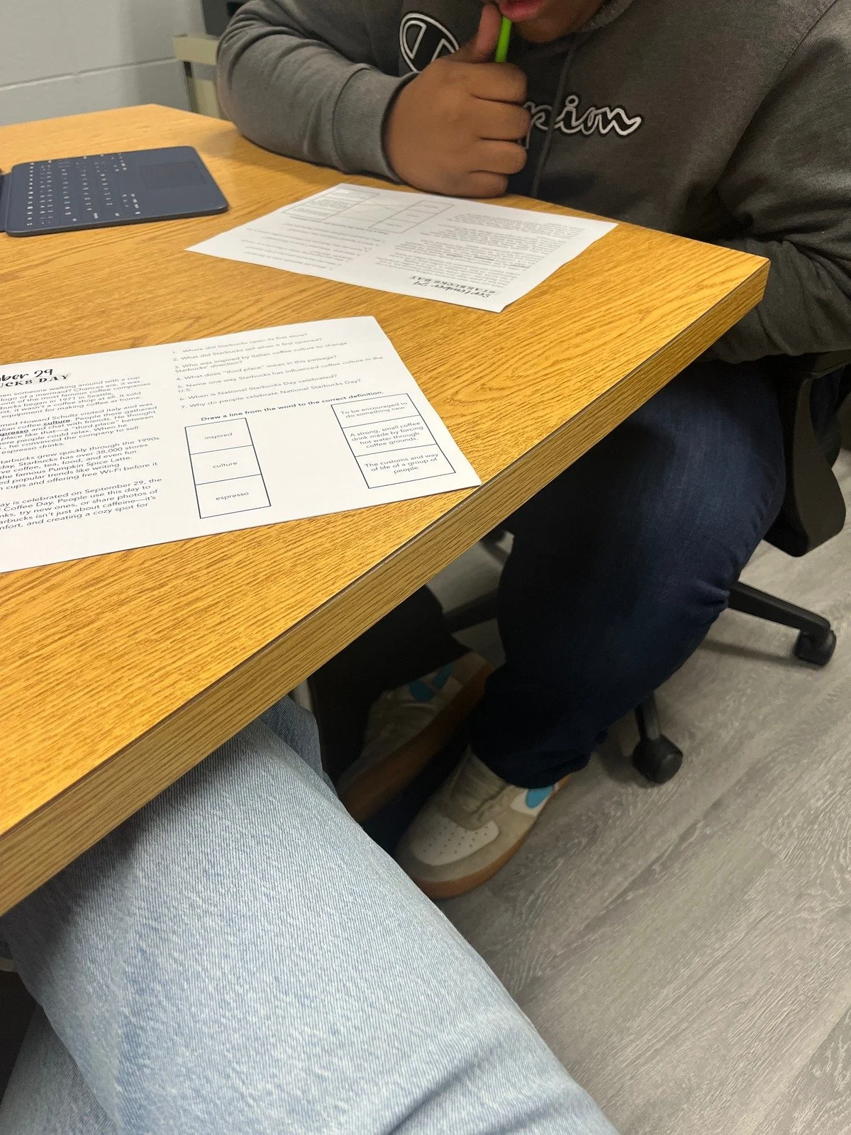 A person sitting at a wooden table with papers and a calculator, holding a highlighter, in an indoor setting.