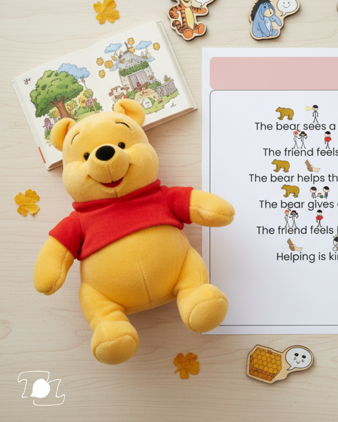 Winnie the Pooh plush toy lying on a wooden surface, surrounded by scattered orange felt leaves, with an open illustrated children's book, a printed story with small animal and human illustrations, a small honey sticker, and two plush character cutouts of Tigger and Eeyore in the background.