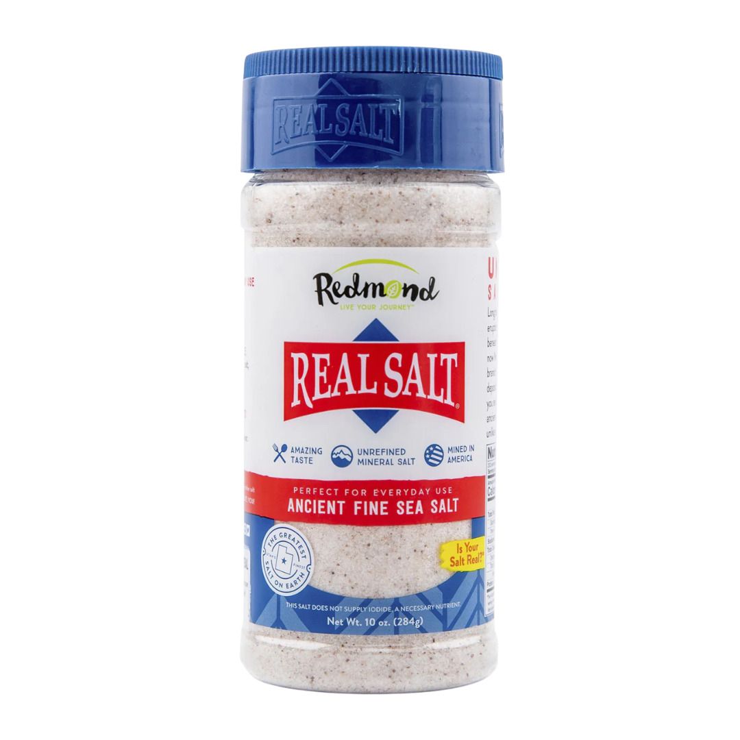 Container of Redmond Real Salt, ancient fine sea salt, with a blue lid and white label featuring red, blue, and green accents.