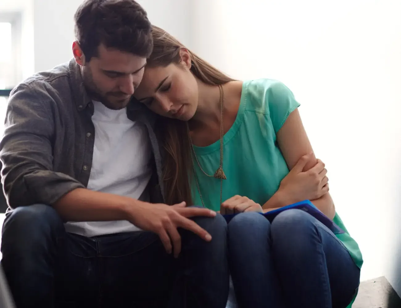 A man and woman relax on a couch, sharing a light moment while looking at each other