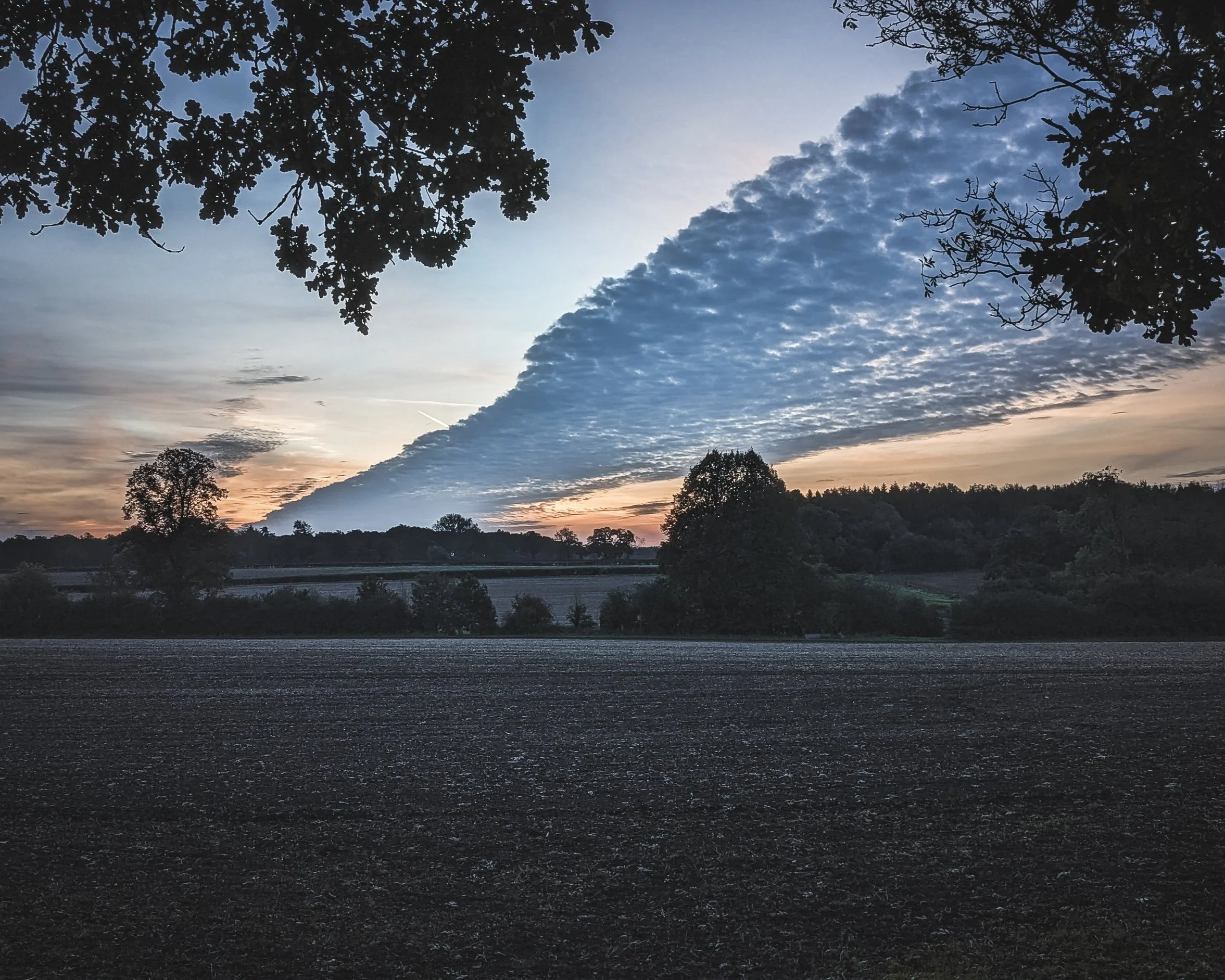 Diagonal cloud formation over sunset field in British autumn countryside