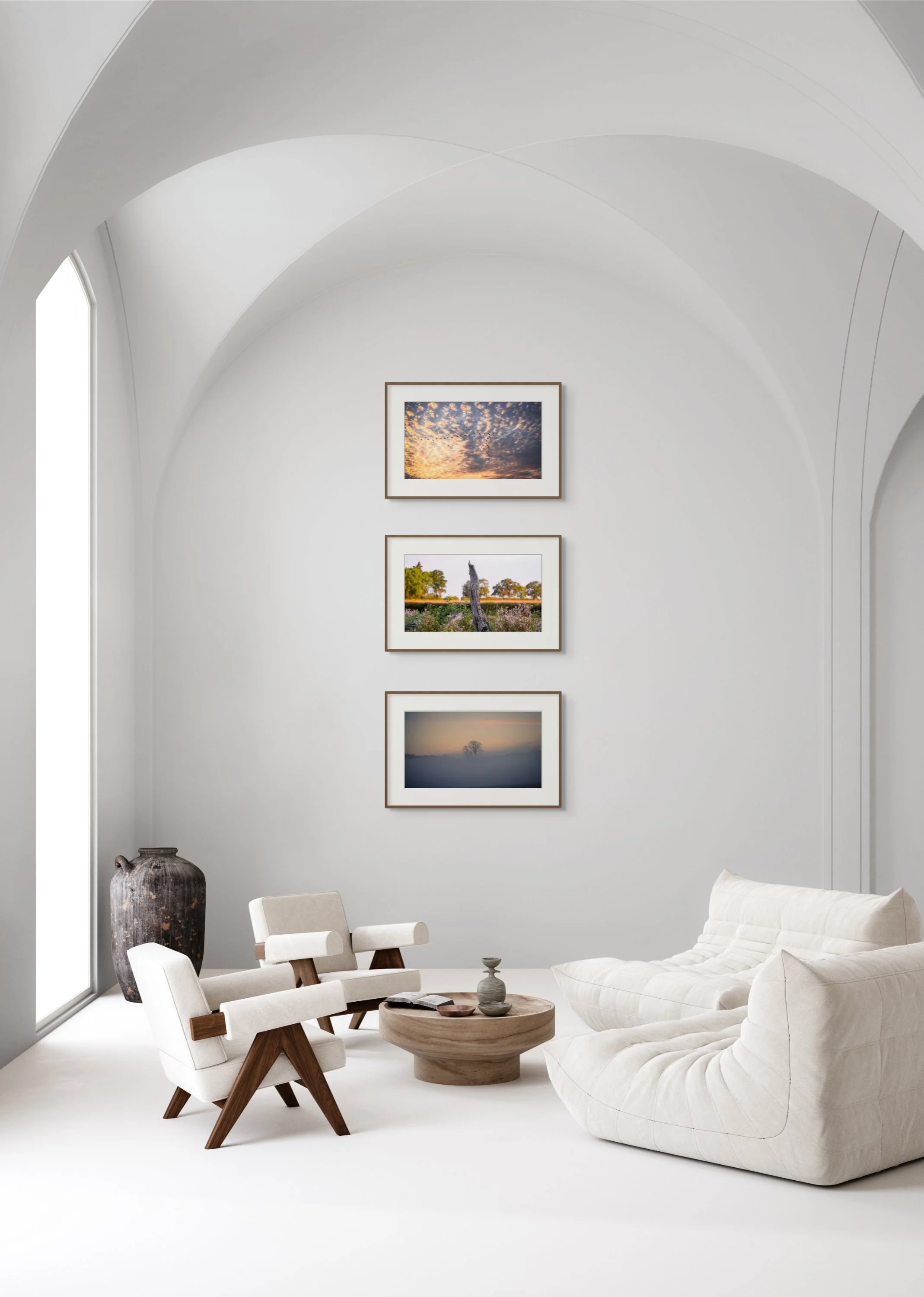 hree framed landscape prints including 'Dead Wood' in a minimalist living room with arched ceiling, white seating, and natural wood accents.